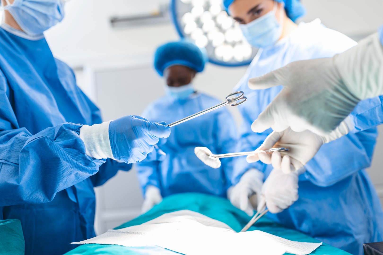 A surgeon and his wearing blue masks performing surgery and swapping instruments.